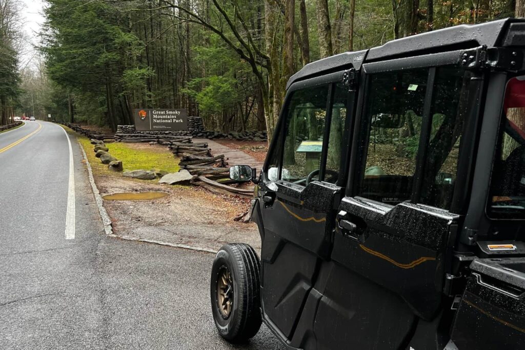 Black UTV rental near the Great Smoky Mountains National Park entrance sign on a rainy day in Pigeon Forge